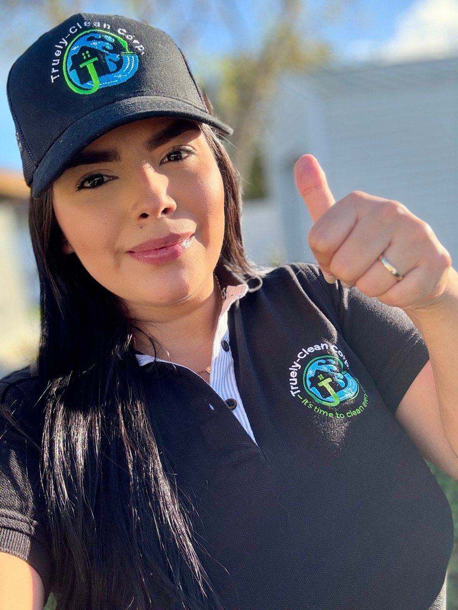 Angely, founder of Truely-Clean Corp., in a branded cap and polo shirt